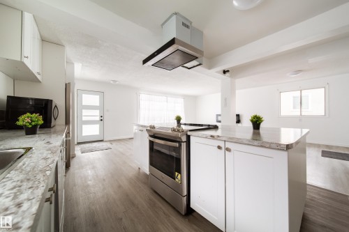 Kitchen featuring white cabinets, stainless steel range oven, extractor fan, light countertops, and dark wood finished floors - 11430 81 Street, Edmonton, AB - Indoor Photo Showing Kitchen With Upgraded Kitchen