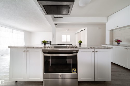 Kitchen with gas stove, white cabinetry, a center island, and dark wood-type flooring - 11430 81 Street, Edmonton, AB - Indoor Photo Showing Kitchen