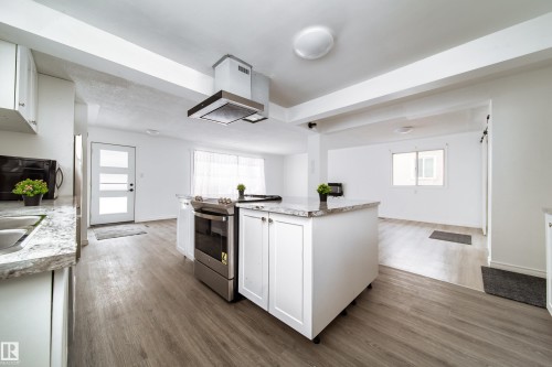 Kitchen featuring white cabinetry, stainless steel electric range oven, island range hood, and dark wood-type flooring - 11430 81 Street, Edmonton, AB - Indoor Photo Showing Kitchen
