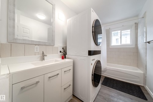 Bathroom featuring vanity, stacked washer and dryer, shower / bath combination with curtain, and light wood-style flooring - 11430 81 Street, Edmonton, AB - Indoor Photo Showing Laundry Room