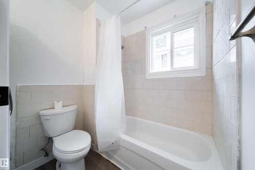 Full bathroom with tile walls, shower / bathtub combination with curtain, and wainscoting - 11430 81 Street, Edmonton, AB - Indoor Photo Showing Bathroom