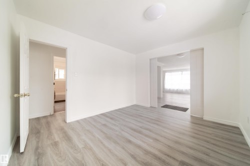 Empty room featuring light wood finished floors and plenty of natural light - 11430 81 Street, Edmonton, AB - Indoor Photo Showing Other Room