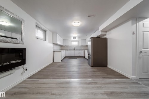 Kitchen with white cabinetry, freestanding refrigerator, light wood-type flooring, and light countertops - 11430 81 Street, Edmonton, AB - Indoor
