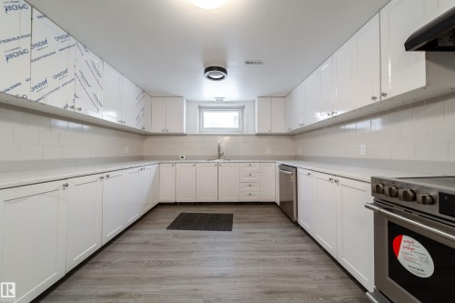 Kitchen featuring white cabinetry, stainless steel appliances, extractor fan, light wood finished floors, and tasteful backsplash - 11430 81 Street, Edmonton, AB - Indoor Photo Showing Kitchen