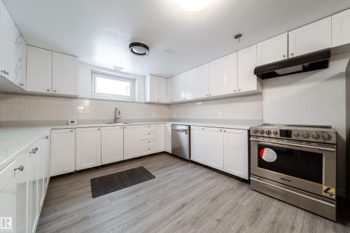 Kitchen featuring white cabinets, stainless steel appliances, light wood-style flooring, and decorative backsplash - 11430 81 Street, Edmonton, AB - Indoor Photo Showing Kitchen