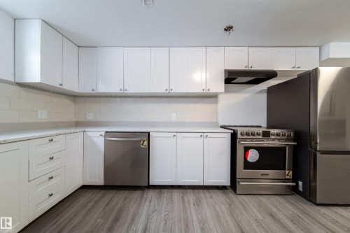 Kitchen featuring white cabinetry, stainless steel appliances, light wood-style flooring, and backsplash - 11430 81 Street, Edmonton, AB - Indoor Photo Showing Kitchen