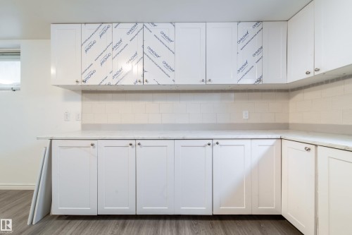 Kitchen with white cabinets, decorative backsplash, wood finished floors, and light stone countertops - 11430 81 Street, Edmonton, AB - Indoor