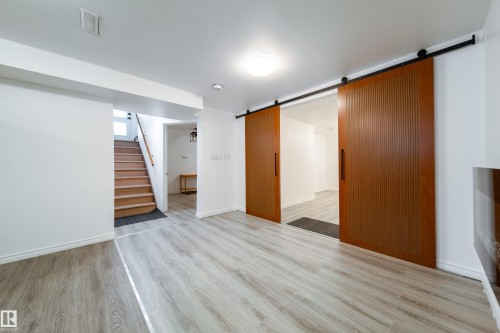 Below grade area featuring a barn door and light wood-style floors - 11430 81 Street, Edmonton, AB - Indoor Photo Showing Other Room