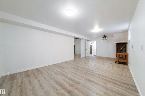 Unfurnished living room with light wood-style flooring and baseboards - 11430 81 Street, Edmonton, AB - Indoor Photo Showing Other Room
