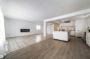 Unfurnished living room with light wood-style floors, a textured ceiling, and a glass covered fireplace - 11430 81 Street, Edmonton, AB  - Indoor 