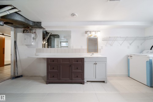 Full bath featuring washer / clothes dryer, vanity, electric panel, and light tile patterned floors - 11430 81 Street, Edmonton, AB - Indoor Photo Showing Laundry Room