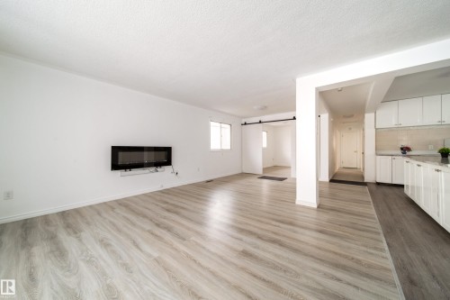 Unfurnished living room featuring a barn door, dark wood-type flooring, and a textured ceiling - 11430 81 Street, Edmonton, AB - Indoor Photo Showing Living Room