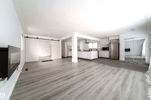 Unfurnished living room with a barn door, dark wood-type flooring, and a textured ceiling - 11430 81 Street, Edmonton, AB - Indoor Photo Showing Other Room