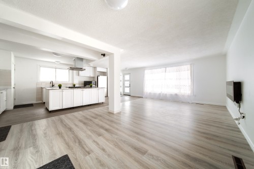 Unfurnished living room with light wood-style flooring and a textured ceiling - 11430 81 Street, Edmonton, AB - Indoor