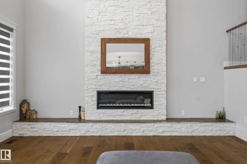 Living area featuring a stone fireplace and wood-type flooring - 4086 Whispering River Drive, Edmonton, AB - Indoor Photo Showing Living Room With Fireplace