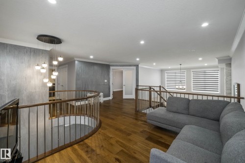 Living room featuring dark wood-style flooring, crown molding, and hanging lights - 4086 Whispering River Drive, Edmonton, AB - Indoor Photo Showing Living Room