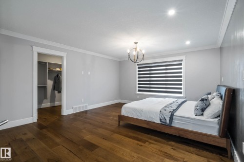 Bedroom with dark wood finished floors, a walk in closet, crown molding, and suspended lighting - 4086 Whispering River Drive, Edmonton, AB - Indoor Photo Showing Bedroom