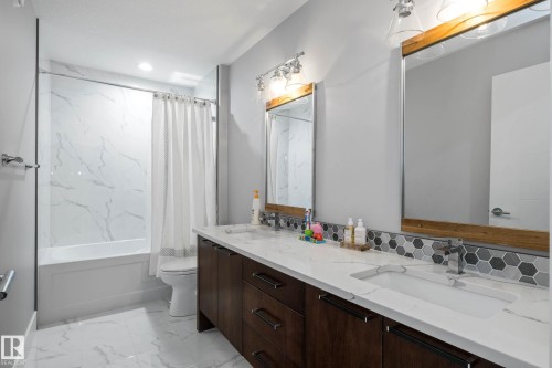 Full bathroom with double vanity, shower / bath combo, and light marble finish floors - 4086 Whispering River Drive, Edmonton, AB - Indoor Photo Showing Bathroom