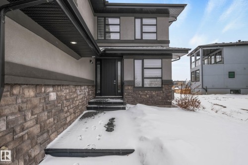 Snow covered property entrance featuring stone siding and stucco siding - 4086 Whispering River Drive, Edmonton, AB - Outdoor