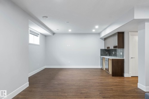 Kitchen featuring tasteful backsplash, dark wood-style floors, light stone counters, dark wood finish cabinets, and a peninsula - 4086 Whispering River Drive, Edmonton, AB - Indoor