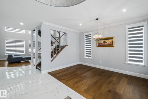 Unfurnished dining area with dark wood-style floors, crown molding, and suspended lighting - 4086 Whispering River Drive, Edmonton, AB - Indoor Photo Showing Other Room