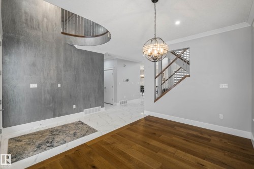 Unfurnished dining area featuring a chandelier, ornamental molding, and wood finished floors - 4086 Whispering River Drive, Edmonton, AB - Indoor Photo Showing Other Room
