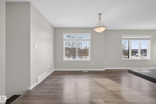 Unfurnished dining area featuring dark wood finished floors and a textured ceiling - 2704 Coughlan Green, Edmonton, AB - Indoor Photo Showing Other Room