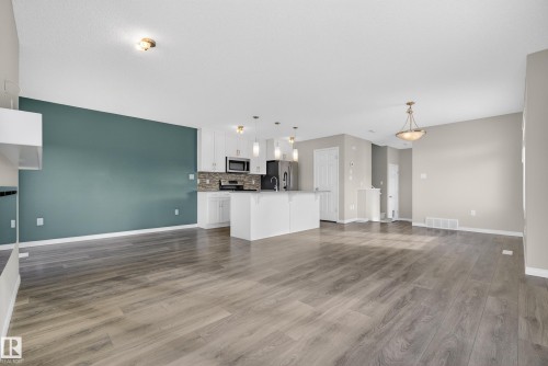 Unfurnished living room featuring dark wood-type flooring and baseboards - 2704 Coughlan Green, Edmonton, AB - Indoor Photo Showing Kitchen