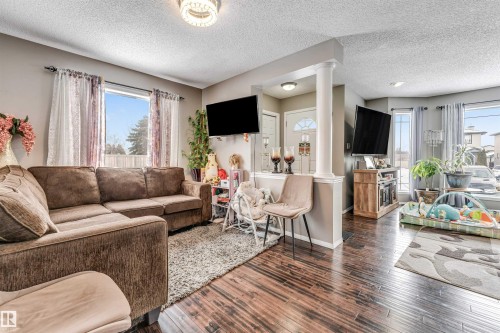 Living room with ornate columns, dark wood finished floors, and a textured ceiling - 4404 150 Avenue, Edmonton, AB - Indoor Photo Showing Living Room