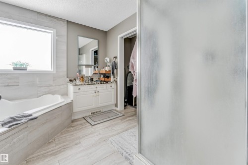 Full bath featuring vanity, a shower stall, a textured ceiling, and a garden tub - 4404 150 Avenue, Edmonton, AB - Indoor Photo Showing Bathroom