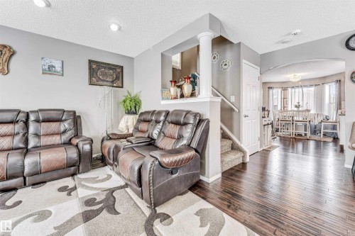Living area with a textured ceiling, wood finished floors, and arched walkways - 4404 150 Avenue, Edmonton, AB - Indoor Photo Showing Living Room