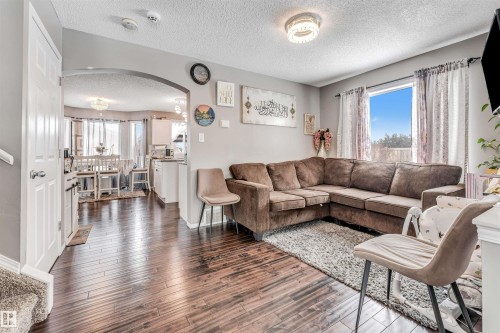 Living area with arched walkways, a textured ceiling, and dark wood finished floors - 4404 150 Avenue, Edmonton, AB - Indoor Photo Showing Living Room