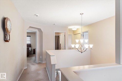 Corridor with a chandelier, light colored carpet, and an upstairs landing - 66 Nadine Way, St. Albert, AB - Indoor