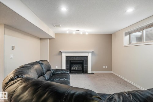 Living room featuring carpet floors, a textured ceiling, and a tiled fireplace - 66 Nadine Way, St. Albert, AB - Indoor With Fireplace