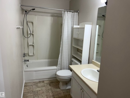 Bathroom with stone finish floors, vanity, and shower / tub combo - 130 1 Street, Blue Ridge, AB - Indoor Photo Showing Bathroom