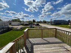 Wooden terrace featuring a residential view, a lawn, and a storage unit - 