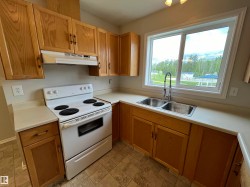 Kitchen with white electric range, light countertops, and stone finish floors - 
