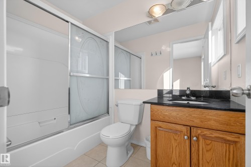 Full bath featuring vanity, combined bath / shower with glass door, and light tile patterned floors - 11435 37A Avenue, Edmonton, AB - Indoor Photo Showing Bathroom