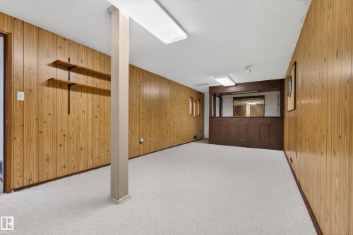 Finished below grade area with wood walls, carpet floors, and a textured ceiling - 11435 37A Avenue, Edmonton, AB - Indoor Photo Showing Other Room