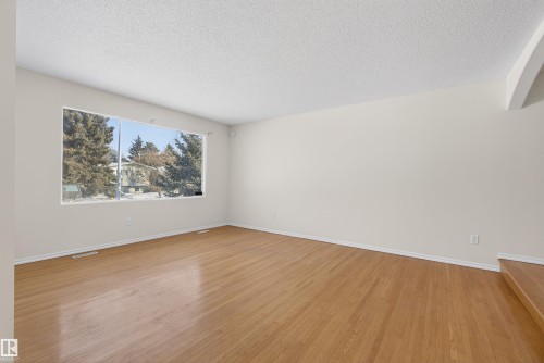 Empty room featuring a textured ceiling and light wood-style flooring - 11435 37A Avenue, Edmonton, AB - Indoor Photo Showing Other Room