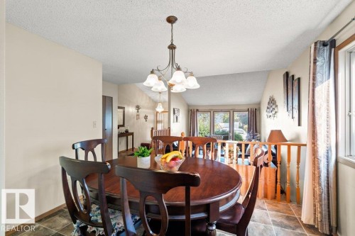 Dining area featuring a textured ceiling, a chandelier, dark stone finish flooring, and lofted ceiling - 10429 28A Avenue, Edmonton, AB - Indoor Photo Showing Dining Room