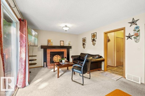 Living room with carpet floors, a textured ceiling, and a brick fireplace - 10429 28A Avenue, Edmonton, AB - Indoor With Fireplace