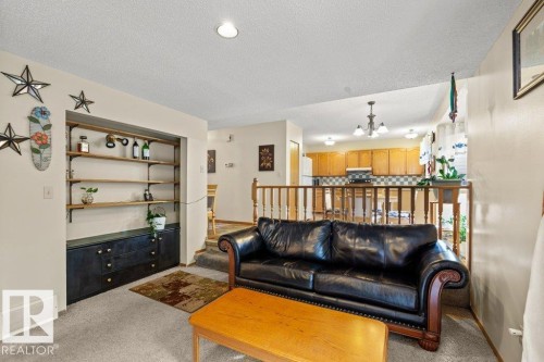 Living room with a chandelier, light colored carpet, and a textured ceiling - 10429 28A Avenue, Edmonton, AB - Indoor Photo Showing Living Room