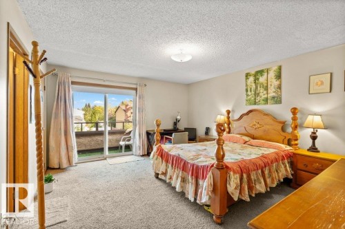 Carpeted bedroom with access to exterior and a textured ceiling - 10429 28A Avenue, Edmonton, AB - Indoor Photo Showing Bedroom