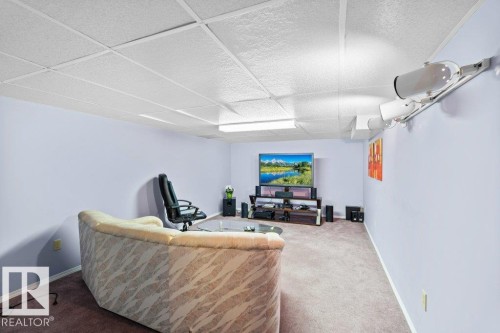 Carpeted living room featuring a drop ceiling and baseboards - 10429 28A Avenue, Edmonton, AB - Indoor