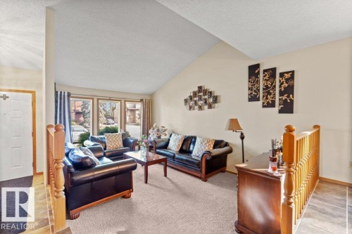 Living room featuring lofted ceiling, light tile patterned floors, a textured ceiling, and light colored carpet - 10429 28A Avenue, Edmonton, AB - Indoor Photo Showing Living Room