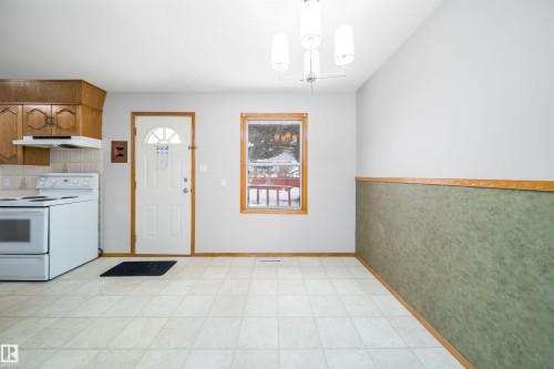 Kitchen with white electric range oven, wood finish cabinets, light countertops, a chandelier, and tasteful backsplash - 8908 130 Avenue Nw, Edmonton, AB - Indoor Photo Showing Kitchen