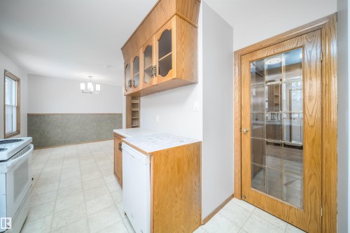 Kitchen featuring light countertops, a relaxing sauna, glass fronted cabinets, white appliances, and wood finish cabinetry - 8908 130 Avenue Nw, Edmonton, AB - Indoor