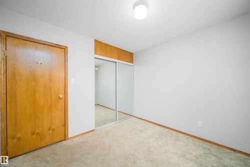Unfurnished bedroom with a closet, a textured ceiling, and light carpet - 8908 130 Avenue Nw, Edmonton, AB - Indoor Photo Showing Other Room