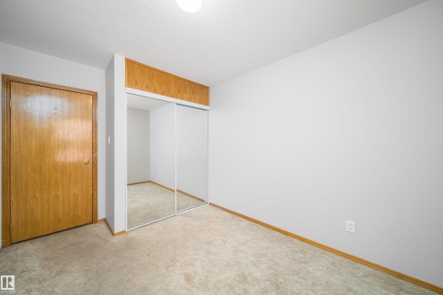 Unfurnished bedroom with a closet, carpet flooring, and a textured ceiling - 8908 130 Avenue Nw, Edmonton, AB - Indoor Photo Showing Other Room
